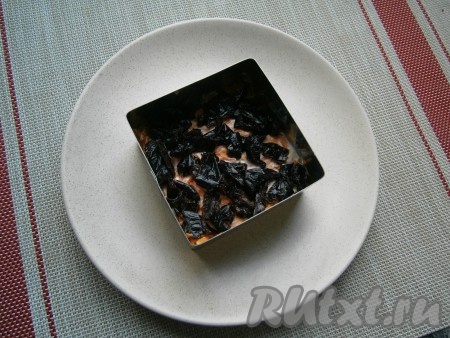 Чернослив вымыть и нарезать его небольшими кусочками (если чернослив сухой, то предварительно залейте его на 10 минут кипятком, а затем обсушите). Выложить чернослив на морковный слой.