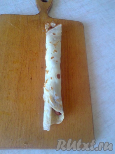 Сверните половинку блина с начинкой в трубочку.