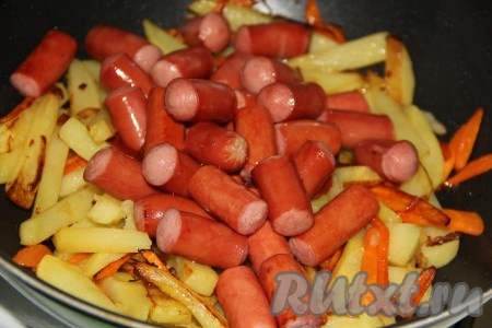 Выложить в сковороду обжаренные сосиски.
