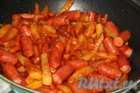 Сюда же добавить нарезанный на пластины очищенный чеснок, соль и специи. Тщательно перемешать жареную картошку с сосисками и тушить на среднем огне, накрыв сковороду крышкой, примерно, 10 минут, иногда перемешивая.
