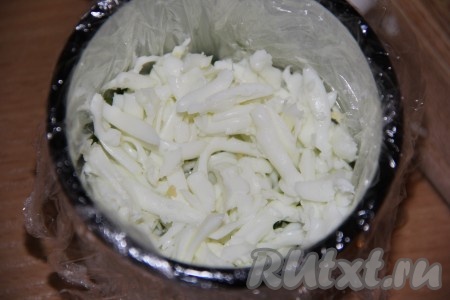 Предварительно сварить 2 яйца (варить в течение 10 минут с начала кипения воды), а затем, дав им остыть, очистить. Разделить варёные яйца на белки и желтки. Белки натереть на тёрке. Половину натёртых белков выложить поверх лука, можно немного посолить, смазать майонезом.
