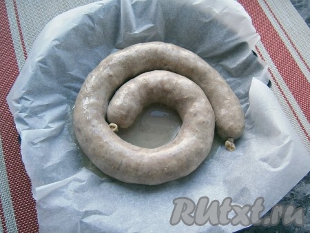 Затем колбасу вынуть и сполоснуть под проточной водой, выложить её в любую форму для запекания, застеленную пергаментом. Налить на дно&nbsp;20-30 мл горячей воды.