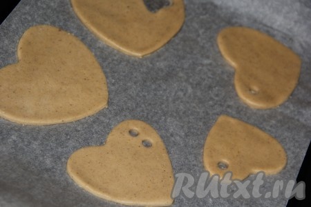 Выложить печенье на противень, застеленный бумагой для выпечки, на небольшом расстоянии друг от друга. В некоторых печенюшках я с помощью коктейльной трубочки сделала отверстия для ленточек.
