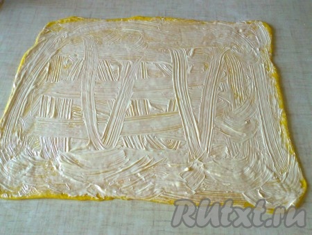 Смажьте раскатанный пласт теста 100 граммами размягчённого сливочного масла.