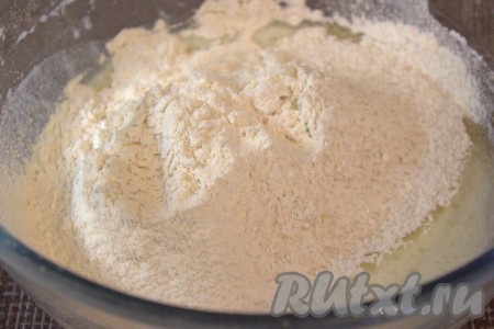 Часть муки просеять и смешать с сухими дрожжами, добавить в миску к кефирной смеси, перемешать.
