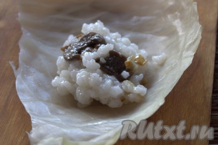 На подготовленный капустный лист выложить по 1-2 столовых ложки начинки из грибов и риса.
