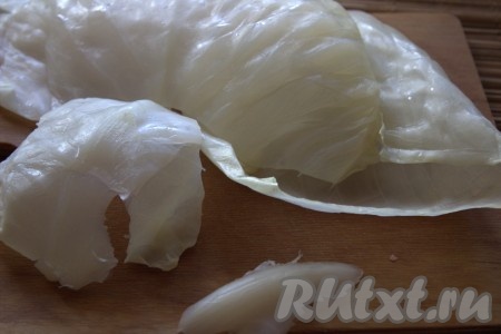 Капустные листья выложить на рабочую поверхность. 3-4 капустных листа отложить в сторонку, мы их выложим на дно формы для запекания и будем использовать, чтобы прикрыть голубцы сверху). С остальных листьев острым ножом срезать твёрдую часть капустного листа.
