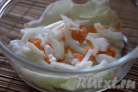 На дно жаропрочной формы выложить 1-2 отложенных капустных листа, затем выложить сырые лук и морковь, которые заранее отложили.
