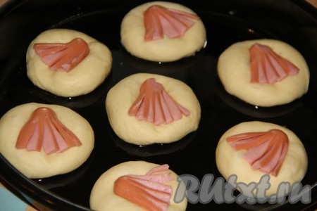 Выложить по одному осьминожку на бороздку на булочке и немного утопить в тесто.
