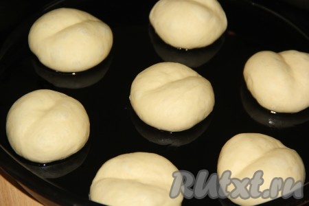 Выложить круглые булочки на расстоянии друг от друга на противень, смазанный растительным маслом, и оставить на 30-40 минут. За это время булочки увеличатся в объёме. Краем ладони на поверхности каждой булочки сделать по середине борозду (как на фото).
