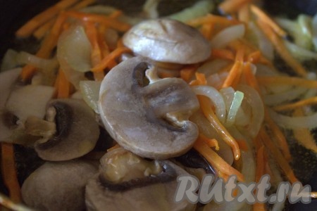 Поместить грибы к луку и морковке, перемешать, обжаривать на среднем огне минуты 2.

