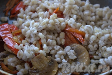 В сковороду к овощам и грибам выложить сваренную перловую крупу.
