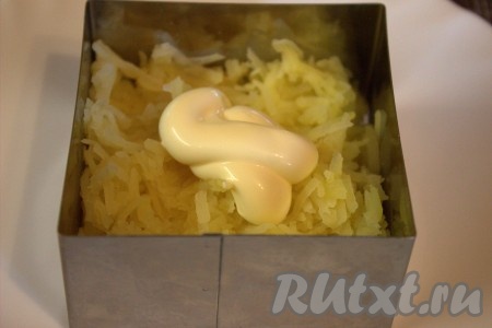 На плоскую тарелку или плоское блюдо (я формировала салат при помощи кулинарной формы) выложить первым слоем натёртый картофель, слегка утрамбовать, по желанию, можно немного посолить, смазать этот слой майонезом.
