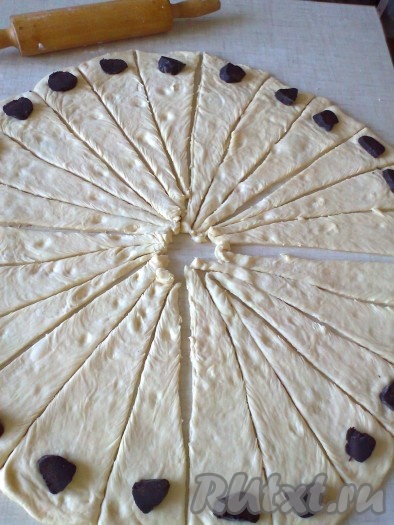 На каждый треугольник теста на широкий край выложите кусочек начинки.