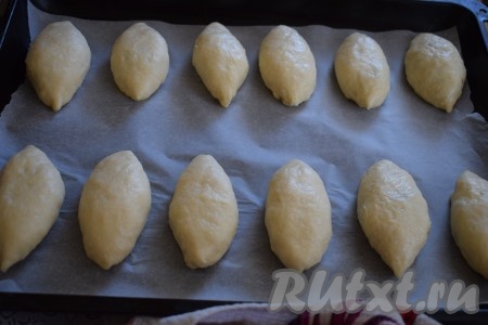 Выкладываем на противень пергамент и перекладываем пирожки, оставляя расстояние между заготовками для того, чтобы у них было свободное место подходить и увеличиваться в размерах в духовке.

