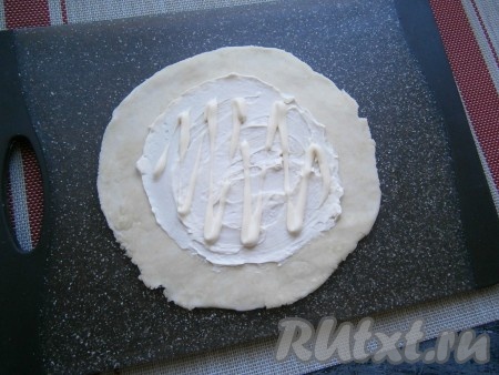 Каждую часть теста раскатать в довольно тонкую лепешку, смазать её, не доходя 3-4 см до краёв, плавленным сыром и майонезом.
