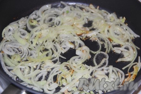 На сковороду влить растительное масло, выложить лук, нарезанный полукольцами, и обжарить его, иногда перемешивая, до золотистого цвета на среднем огне. Обжаренный лук переложить на тарелку.
