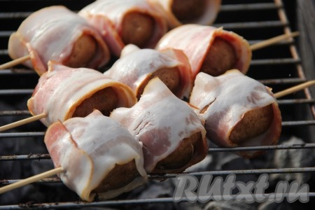 Выложить шампиньоны в беконе на мангал с горячими углями.
