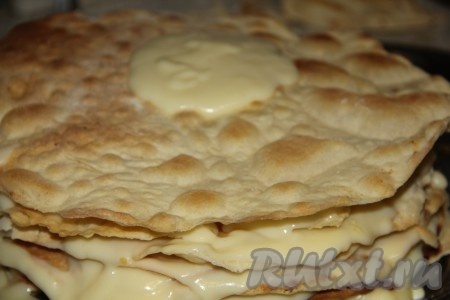 Приступаем к формированию классического "Наполеона". Один корж откладываем, его мы будем использовать для посыпки торта. Смазываем коржи остывшим заварным кремом и складываем их друг на друга. Я использую примерно один половник крема для смазывания одного коржа. Верх торта тоже смазываем кремом.