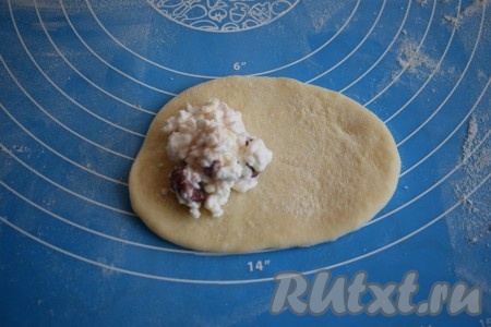 Далее каждый шарик раскатываем в овал и отрезаем от него небольшой кусочек теста, который пойдёт на украшение - завязку-поясок. На середину овала выкладываем 1 столовую ложку творожно-вишнёвой начинки.
