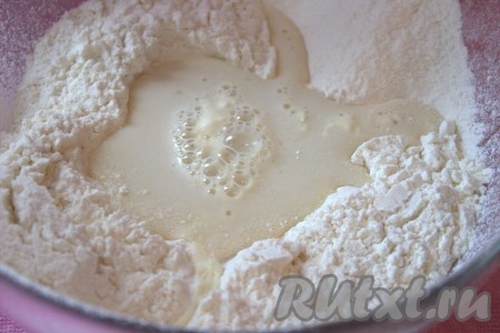 В миску просеять муку. В просеянной муке сделать углубление, влить молочно-дрожжевую смесь, смешанную с заварной основой. Тщательно перемешать, постепенно смешивая муку с жидкими ингредиентами, чтобы не забить тесто мукой.
