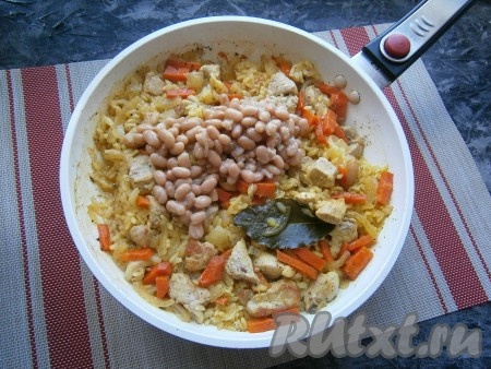 Готовить рис с мясом на малом огне под закрытой крышкой до испарения всей жидкости (около 20-25 минут), после чего добавить в сковороду отваренную (или консервированную) фасоль.
