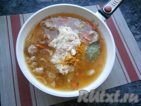 Далее добавить промытый несколько раз рис, очищенные зубчики чеснока (целые), лавровый лист, специи, карри и куркуму, влить горячую воду.
