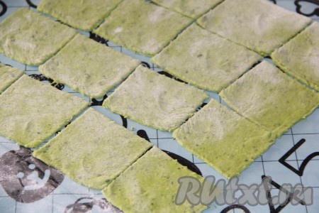 Готовое зелёное тесто выложить на припыленную мукой поверхность и тонко раскатать скалкой. Я делала пельмени в виде ушек, поэтому тесто нарезала на квадратики. Можно сформировать пельмени любой формы.
