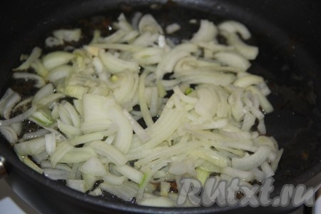 Лук почистить, нарезать тонкими полукольцами, выложить в сковороду, где жарили курицу, и обжарить его, помешивая, до золотистого цвета.
