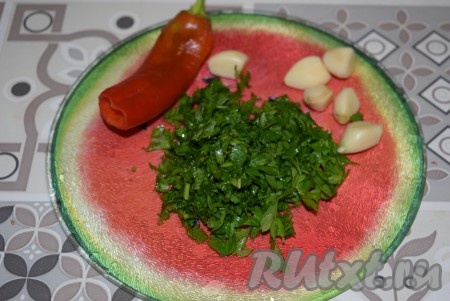 Пока овощи остывают, подготовим нашу ароматную заправку. Для этого измельчим зелень, мелко нарежем острый перец (если не любите острые блюда, можете его и не добавлять), пропустим чеснок через пресс.
