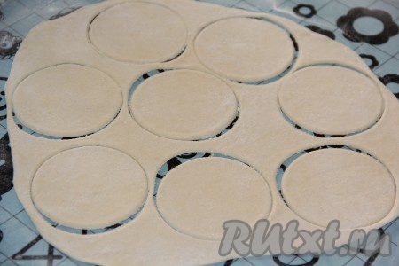 Тесто на столе, присыпанном мукой, тонко раскатать скалкой и вырезать кружочки с помощью рюмки.
