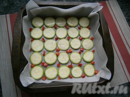 Между кружочками кабачка выложить нарезанный небольшими кубиками сладкий болгарский перец красного цвета, чуть посолить и сбрызнуть всё растительным маслом.
