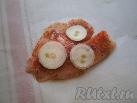 Выложить филе тилапии на лист пергамента, сверху разместить 3-4 колечка репчатого лука, сбрызнуть рыбу растительным маслом.
