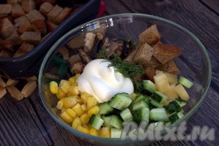 В глубокой миске соединить нарезанные огурцы, сыр, шпроты, добавить кукурузу, заранее слив жидкость, остывшие сухарики и измельчённый укроп, заправить салат майонезом, приправить специями по вкусу, перемешать, при необходимости, посолить.