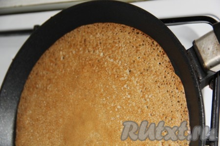 На хорошо разогретую сковороду (перед жаркой первого блинчика можно, по желанию, смазать сковороду маслом) влить часть теста, затем равномерно его распределить и жарить блин с двух сторон до золотистого цвета на среднем огне. В процессе жарки на поверхности блинчика появятся небольшие дырочки. Готовый блин переложить на тарелку. Таким образом пожарить оставшиеся блины, складывая их постепенно аппетитной стопочкой на тарелку. 
