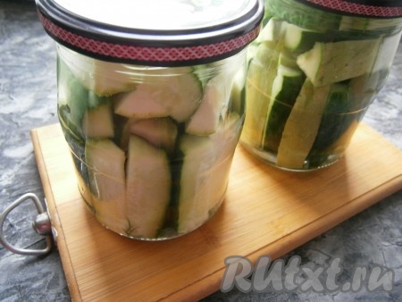 Залить банки с огурцами и кабачками кипятком, прикрыть крышками и оставить на 10 минут. Затем воду из банок перелить в кастрюлю, снова её вскипятить и залить кабачки с огурцами кипятком ещё на 5 минут.
