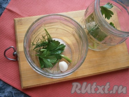 На дно чистых баночек выложить по зубчику чеснока, по 2 веточки укропа и по веточке петрушки.