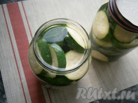 Залить банки с кабачками кипящей водой до самого горлышка, прикрыть банки прокипячёнными крышками, оставить минут на 15. Затем воду из баночек с кабачками слить в раковину, снова влить в банки кипяток и оставить на 15 минут.
