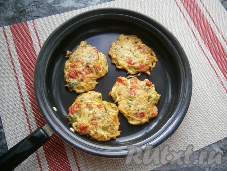 В сковороде разогреть растительное масло. Затем по 1 столовой ложке выкладывать тесто из кабачков и помидоров в виде круглых оладий. Жарить оладьи на среднем огне до румяности с двух сторон.