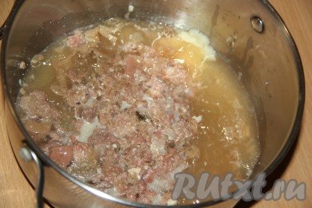 В кастрюлю с толстым дном выложить тушёнку вместе с жиром и размять вилкой.