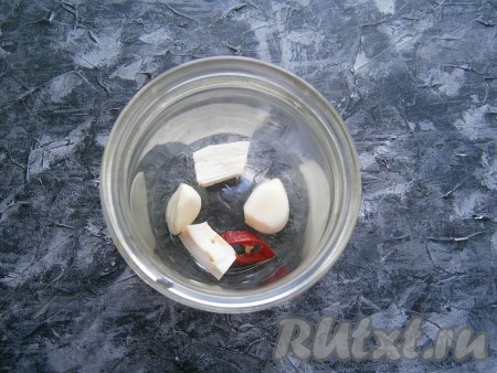 В каждую простерилизованную баночку поместить 2 зубчика чеснока, колечко перца чили, кусочек корня хрена.
