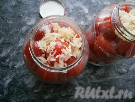 В банки поверх помидоров разместить, чеснок, предварительно очищенный и натёртый на мелкой тёрке (или пропущенный через пресс). В каждую банку объёмом 1,5 литра понадобится около 1 столовой ложки натёртого чеснока.
