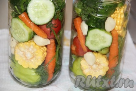 Овощи предварительно вымыть, огурцы нарезать толстыми кольцами, чеснок и морковку почистить, початок кукурузы нарезать на толстые кружочки (1,5-2 см толщиной). Болгарский перец я разрезала на 2 части, семечки с плодоножкой оставила. Выложить овощное ассорти в банки в хаотичном порядке.
