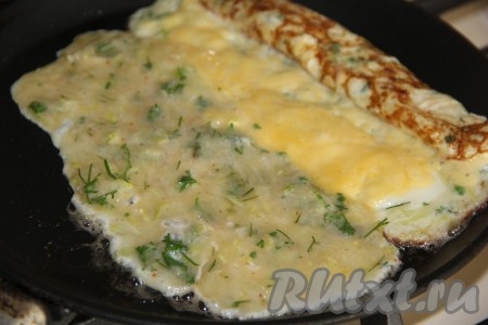 Как только омлет "схватится", аккуратно его свернуть в рулет и сдвинуть на край сковороды, а на чистый край сковородки влить ещё 2 столовые ложки массы так, чтобы яично-кабачковая масса соединилась с краем рулета (как на фото). Снова присыпать сыром. Когда масса "схватится", снова свернуть омлет в рулет.