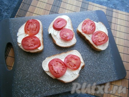 Яйцо сварить вкрутую (на это понадобится минут 10 с начала кипения воды), затем дать ему остыть и очистить его от скорлупы. Ломти батона смазать небольшим слоем сливочного масла, сверху выложить по 2 кружочка свежего помидора, немного посолить.