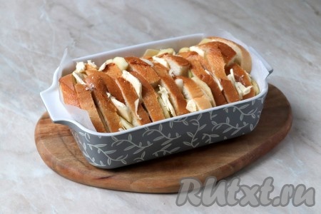 В жаропрочную форму (у меня размер формы 20x12 см), чередуя, выложите хлеб, подготовленные яблоки и тонкие полосы сливочного масла (как на фото).
