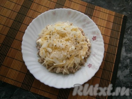 Яблоко вначале очистить от кожуры и семян, а затем натереть его на крупной тёрке, разместить третьим слоем. На яблоки выложить очищенный и нарезанный тонкими четвертинками репчатый лук, посолить, поперчить.
