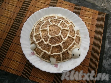 Несколько ложек майонеза выложить в кулинарный одноразовый мешок, обрезать кончик и аккуратно нанести рисунок по салату, который будет похож на панцирь черепахи, как на фото.
