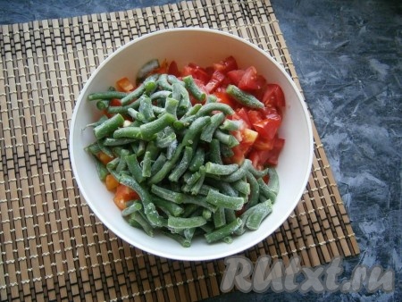 У свежей стручковой фасоли отрезать "хвостики" с двух сторон, а затем нарезать стручки на несколько частей (у меня свежемороженая фасоль), выложить к нарезанным овощам, перемешать.
