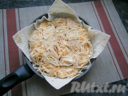 Дать рулетам пропитаться минут 5 и нарезать их на части (небольшие рулетики) толщиной около 2-3 см или так, чтобы они не были выше бортиков вашей сковороды. Лучше, если рулетики будут ниже высоты сковороды на 2-3 см. Выложить рулетики в сковороду, в основной лаваш, поплотнее друг к другу.
